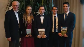 Prof. Heißenhuber with the four winners of the best overall degrees, holding books related to agriculture