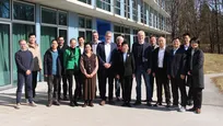 17 Personen stehen vor einem Gebäude mit Glasfront. Sie posieren für das Gruppenbild. In der Mitte stehen die Vertreter der Technischen Universität München und die Vizepräsidentin der Nanjing Agricultural University.